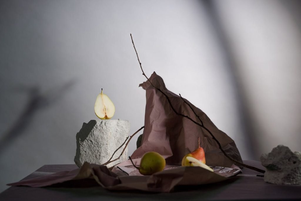 A creative still life arrangement featuring pears, branches, and stones.