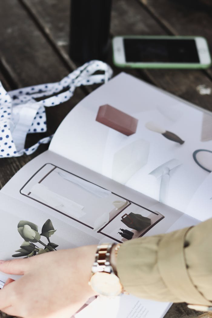 Close-up of a person flipping through a fashion magazine outdoors, showcasing elegant designs.