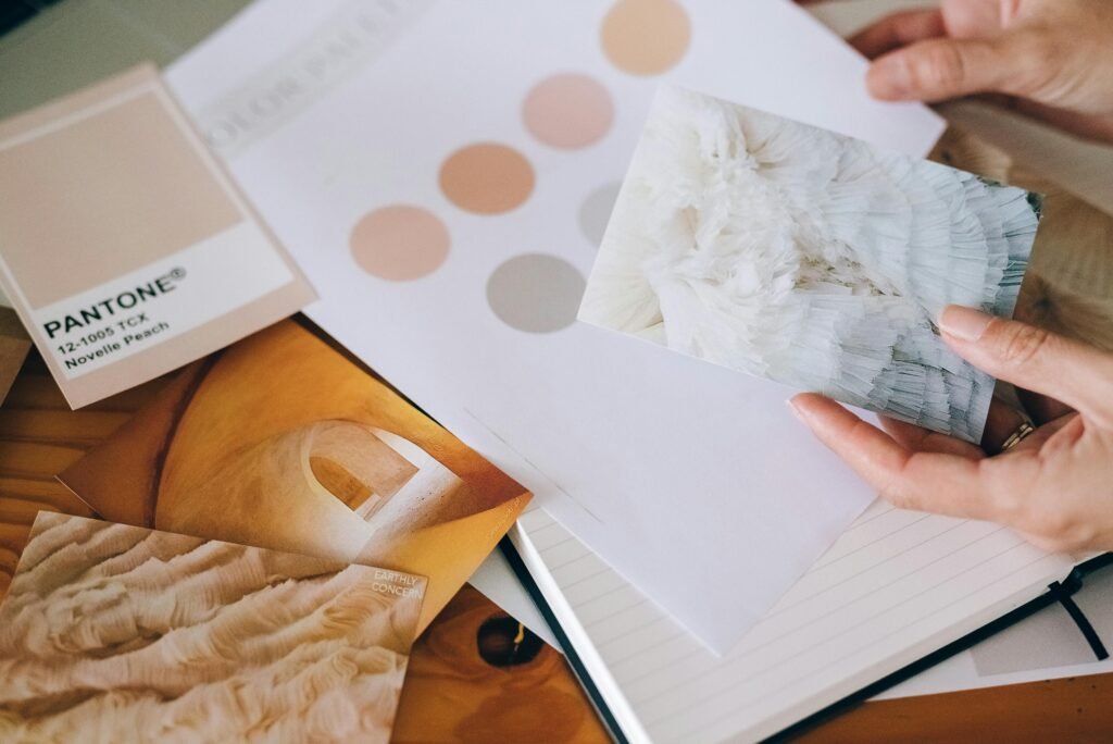 Hands holding Pantone swatches and textured cards for design inspiration.